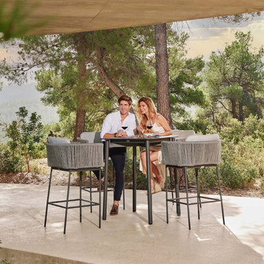 Couple sitting at an outdoor dining table with chairs in a forest setting