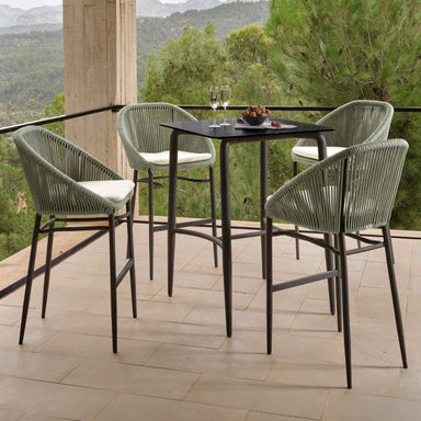 Outdoor dining set with four chairs and a table on a patio with a scenic background.