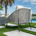 Outdoor patio chair with cushions on a grassy area with a pool and palm tree in the background.