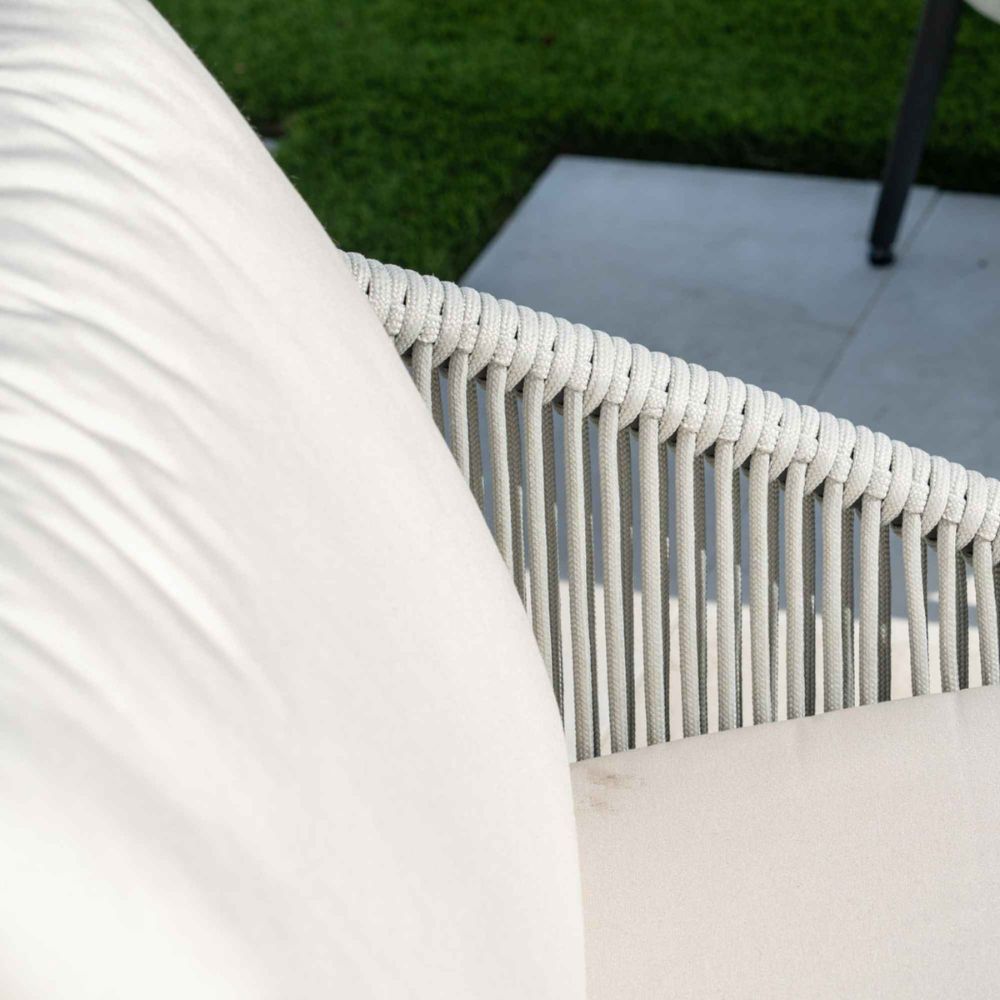 Close-up of a white wicker chair with a blurred green outdoor background