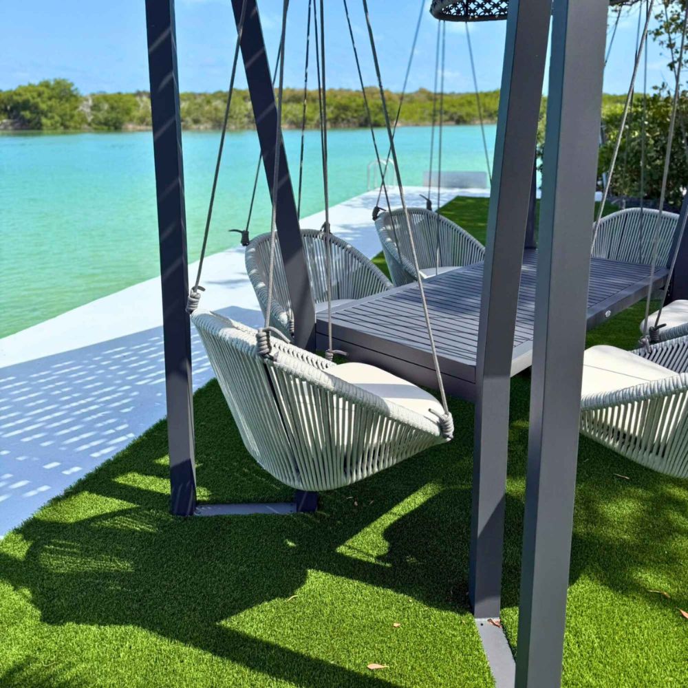 Swing chairs by a body of water with greenery in the background
