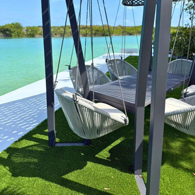 Swing chairs by a body of water with greenery in the background