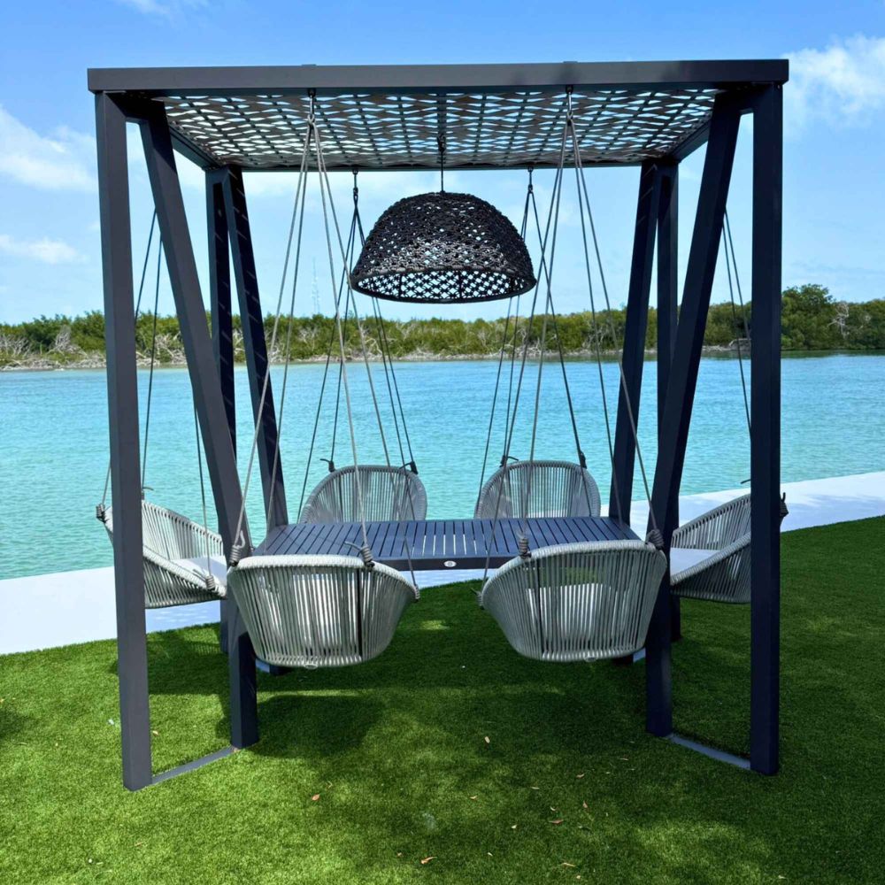 Outdoor swing set with table and chairs under a canopy by a lake.