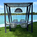Outdoor swing set with table and chairs under a canopy by a lake.