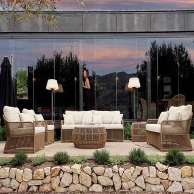 Outdoor patio set with wicker chairs and white cushions in a modern garden setting.