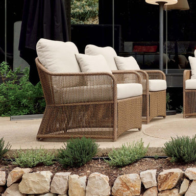 Wicker outdoor furniture set with white cushions on a patio.