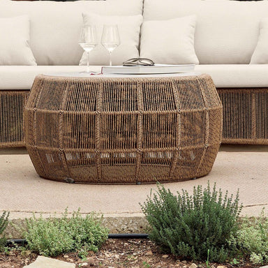 Wicker coffee table in front of a white sofa with plants in the foreground.