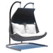 Hanging chair with black wicker design and white cushions on a white background