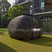 Spherical outdoor lounge chair on a grassy area with a modern building in the background
