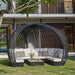 Modern outdoor patio set with a circular wicker chair and sofa on a grassy area.