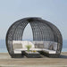 Outdoor patio furniture set with a circular wicker canopy on a wooden deck by the sea.