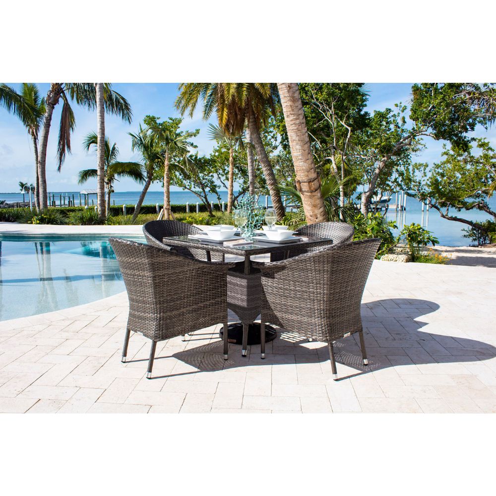 Outdoor patio set with table and chairs by a poolside with palm trees and ocean view.