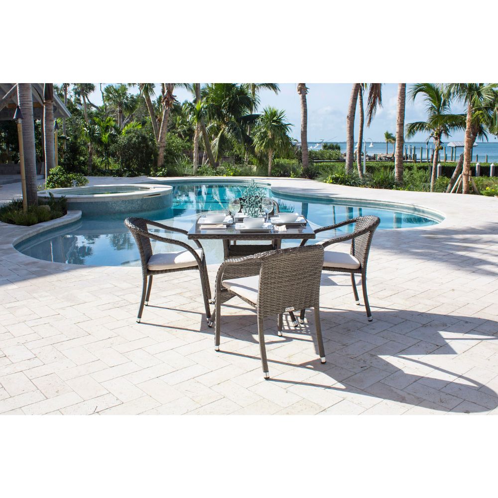 Outdoor dining set by a pool with palm trees in the background