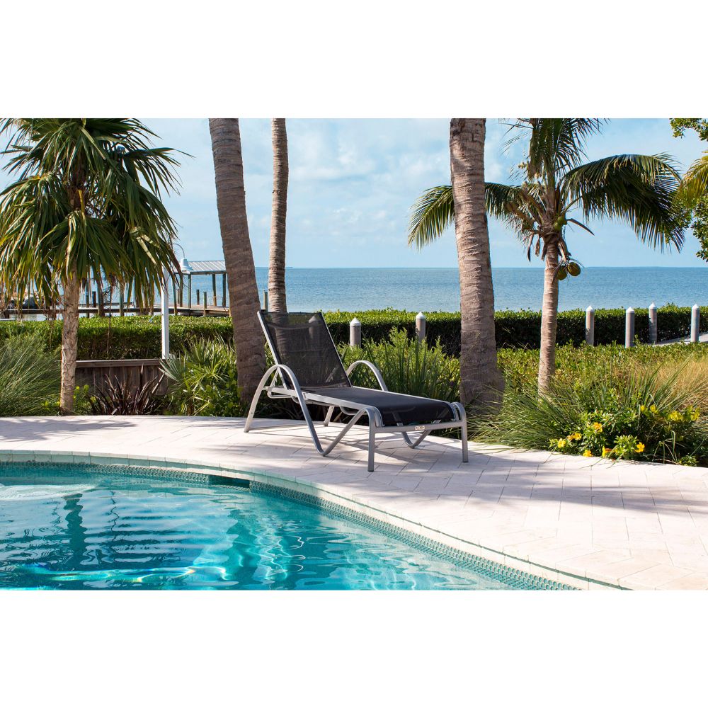 Poolside lounge chair with palm trees and ocean view