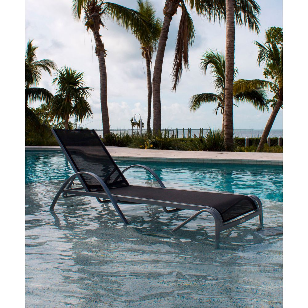 Black lounge chair by a pool with palm trees in the background