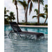 Black lounge chair by a pool with palm trees in the background