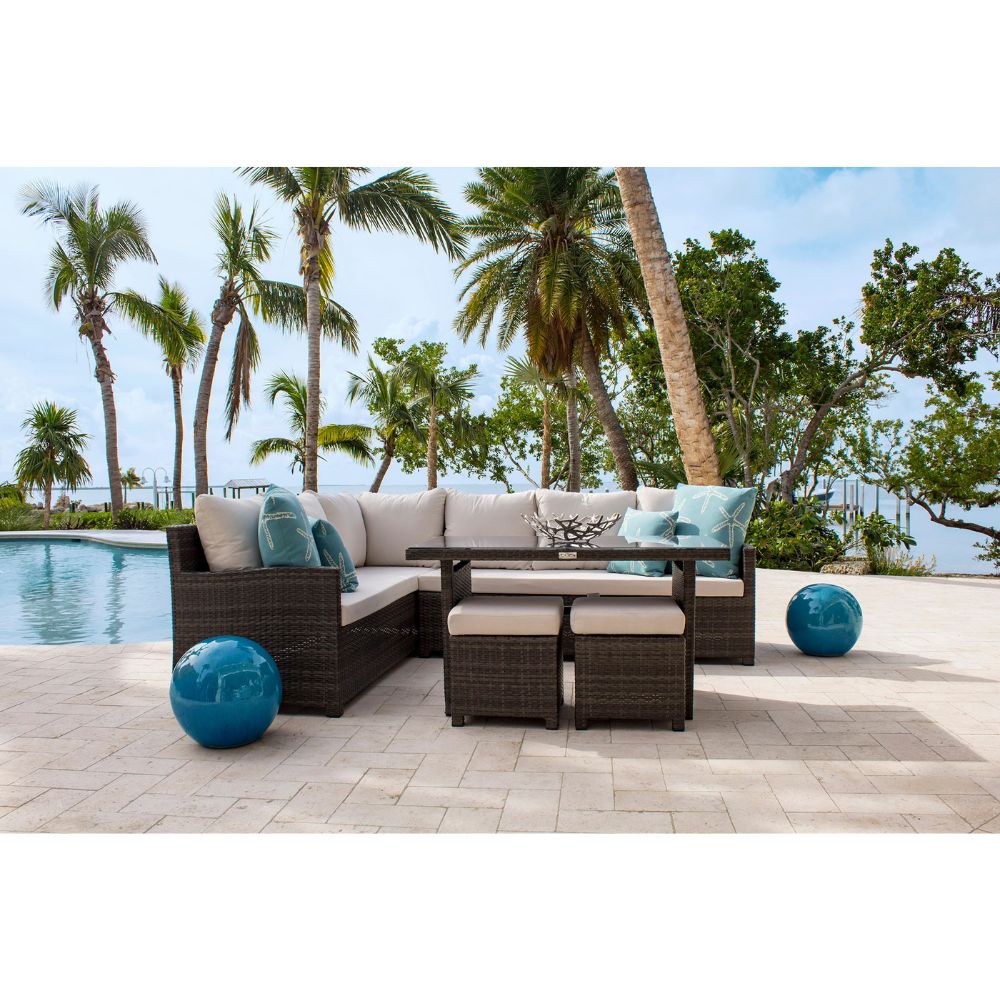 Outdoor patio furniture set with palm trees and pool in the background