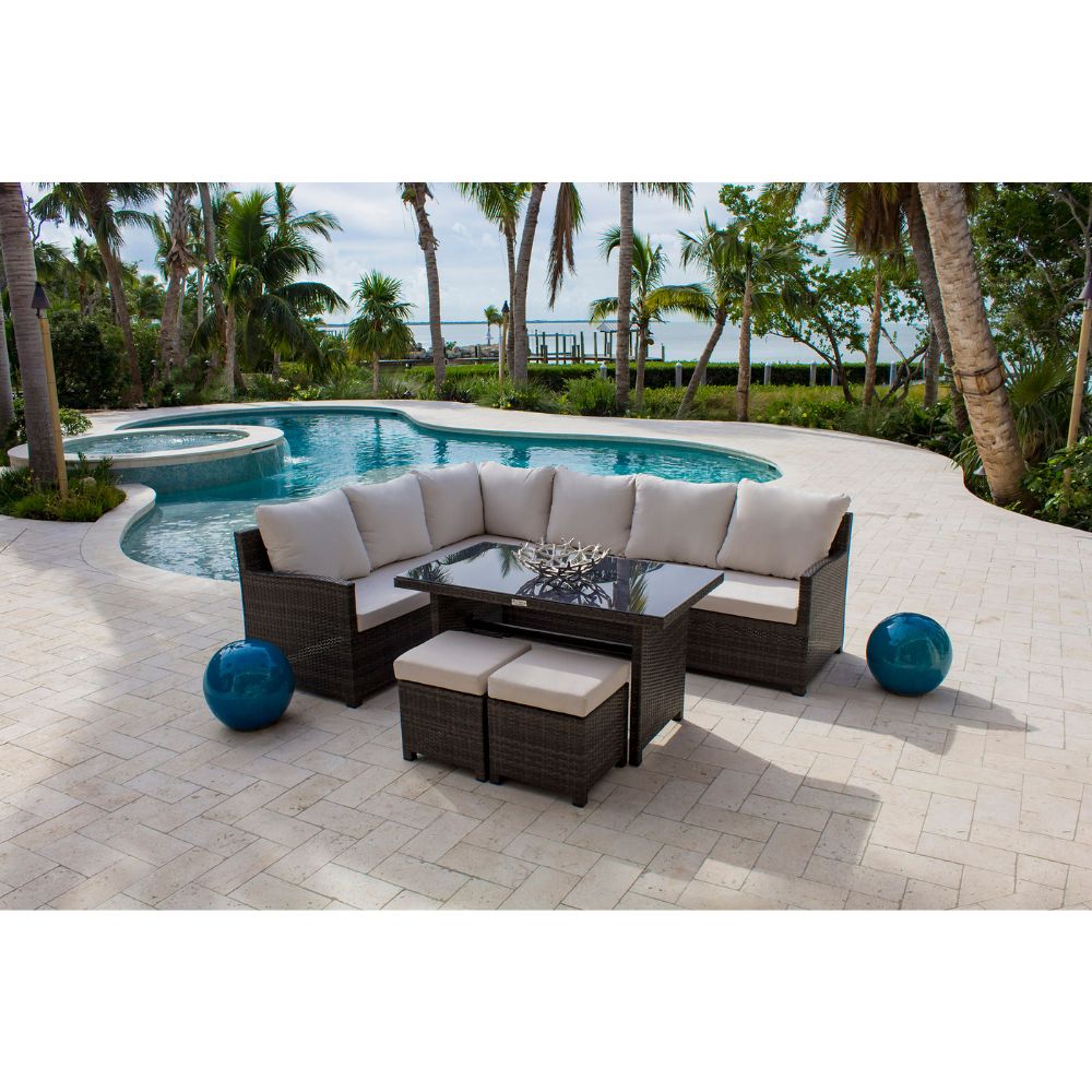 Outdoor patio furniture set with a pool and palm trees in the background