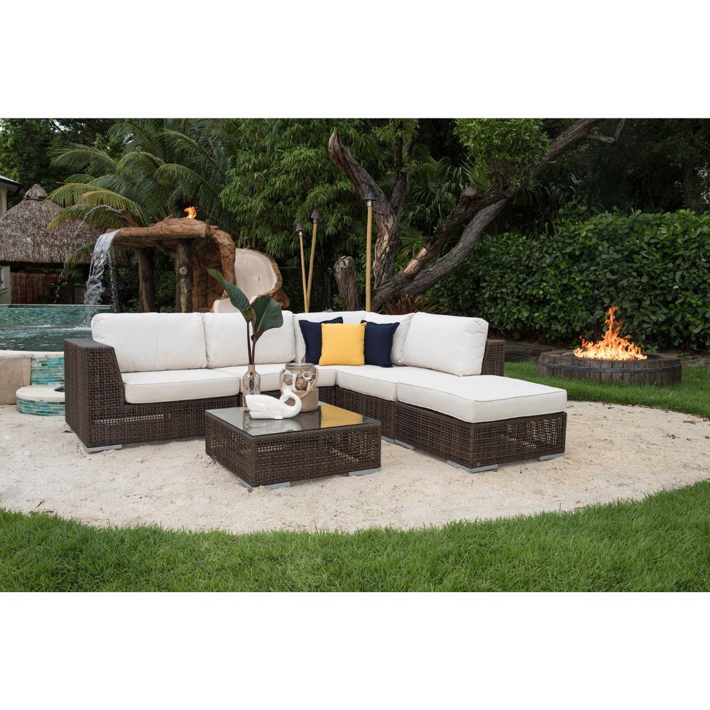 Outdoor patio furniture set with white cushions and a fire pit in the background.