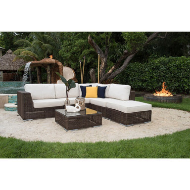 Outdoor patio furniture set with white cushions and a fire pit in the background.