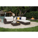 Outdoor patio furniture set with white cushions and a fire pit in the background.
