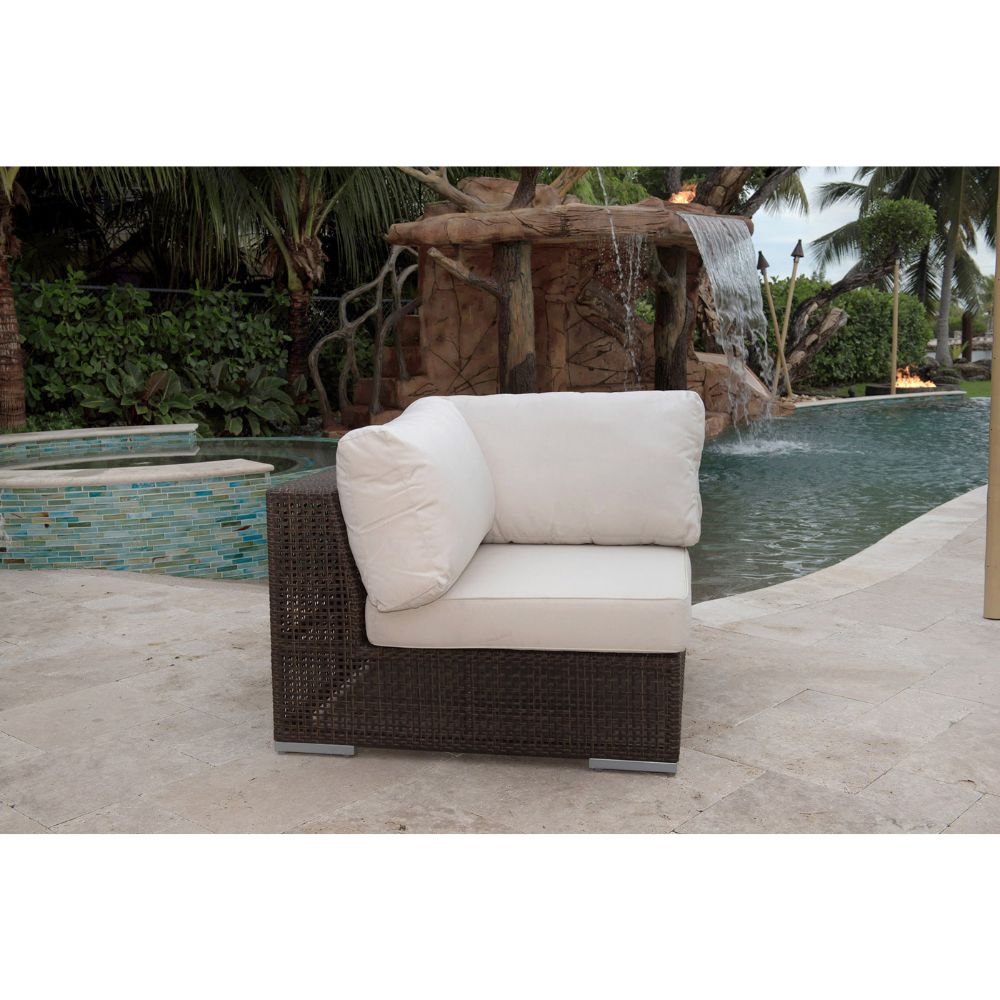 Wicker outdoor chair with beige cushions in front of a water feature