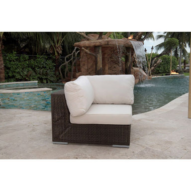 Wicker outdoor chair with beige cushions in front of a water feature