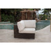 Wicker outdoor chair with beige cushions in front of a water feature