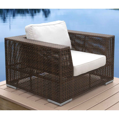Wicker outdoor chair with white cushions on a wooden deck by a body of water.