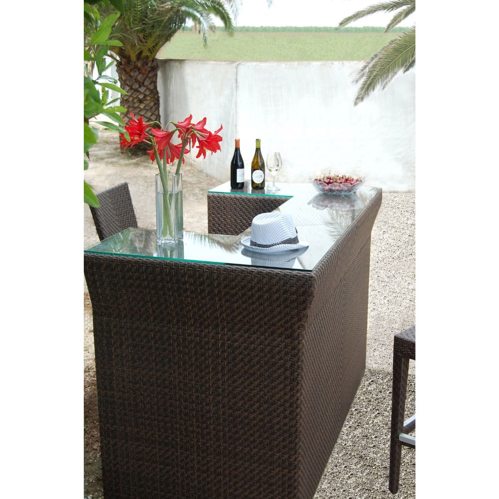 Outdoor patio table with chairs, flowers, and wine glasses on a sunny day.