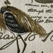 Close-up of a embroidered bird design on fabric with text in the background