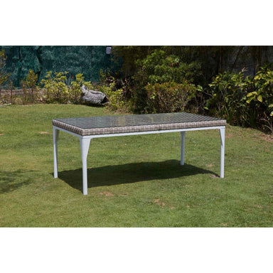Garden table with a textured top on grass with bushes in the background