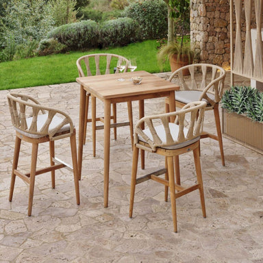 Outdoor dining set with wooden table and chairs on a stone patio.