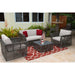 Outdoor patio furniture set with gray wicker chairs and white cushions on a red and beige rug.