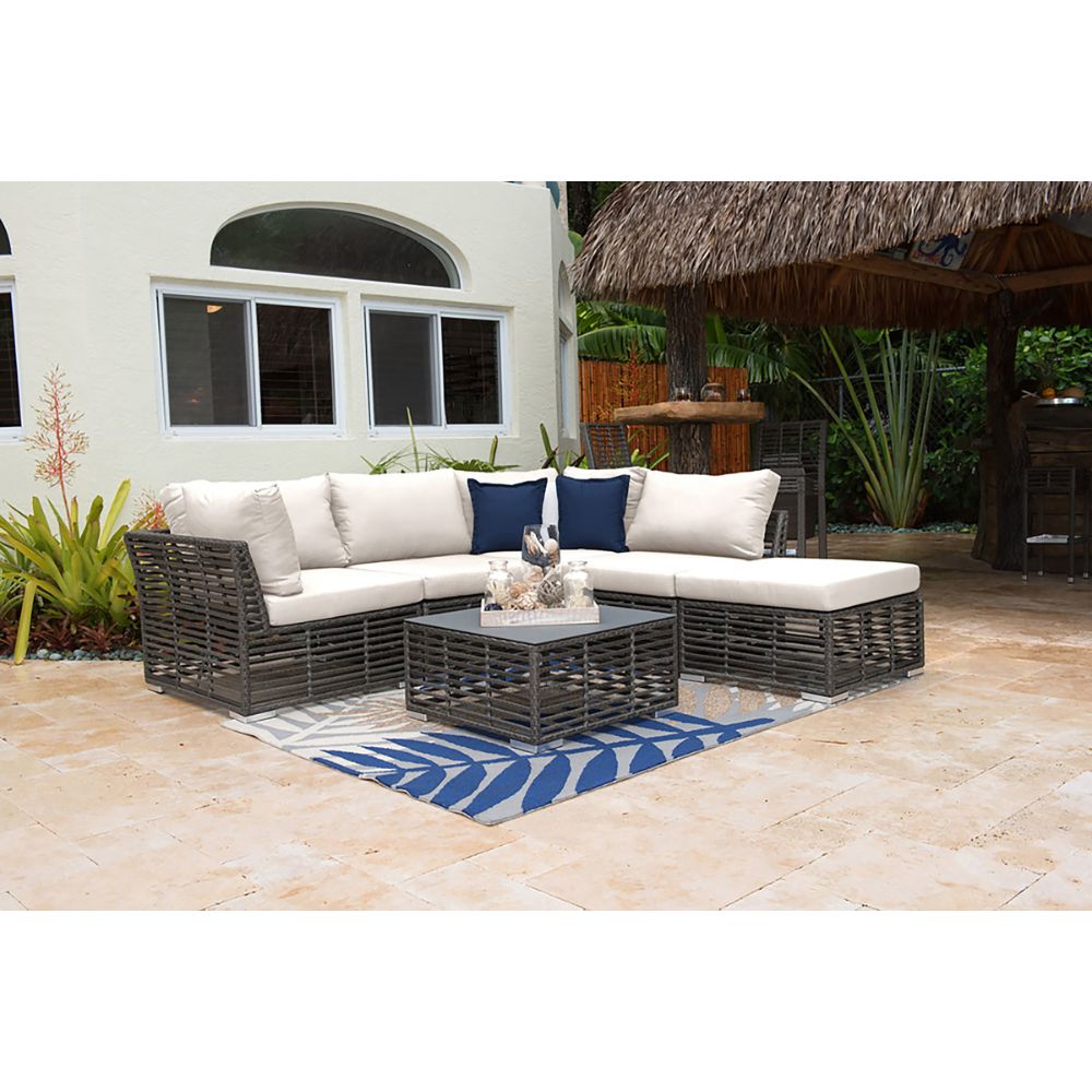 Outdoor patio set with a sectional sofa and coffee table on a stone patio.