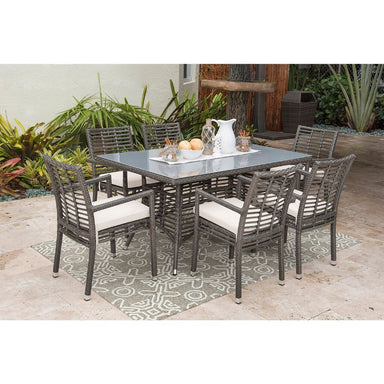 Outdoor patio set with table and chairs on a patio with plants in the background