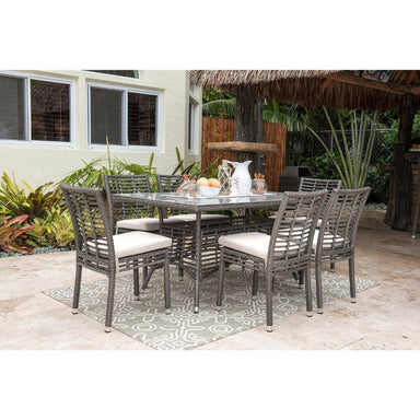 Outdoor patio set with table and chairs on a patio with plants and a building in the background