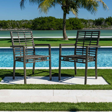 Two wooden chairs by a pool with a palm tree and greenery in the background