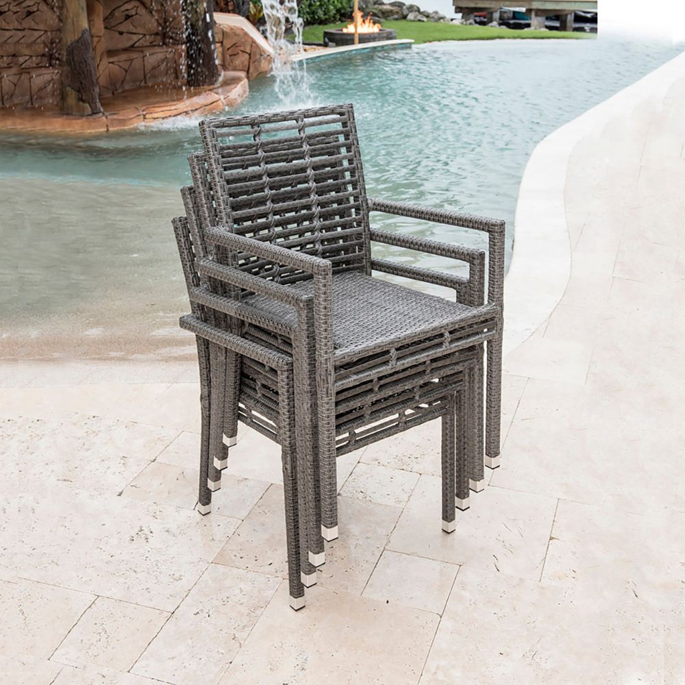 Gray wicker chairs stacked by a pool with water features in the background