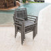 Gray wicker chairs stacked by a pool with water features in the background