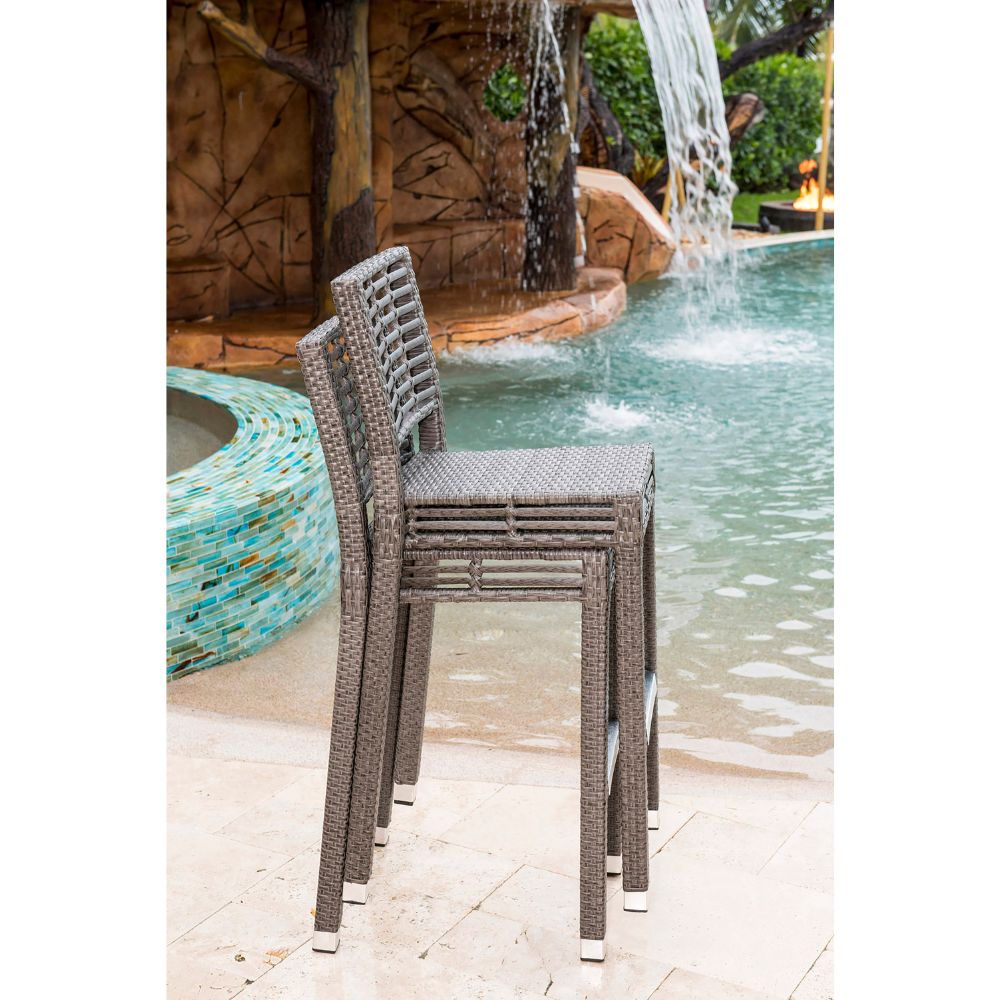 Wicker chairs by a pool with a waterfall in the background