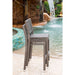 Wicker chairs by a pool with a waterfall in the background