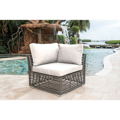 Outdoor wicker chair with white cushions by a poolside with water feature