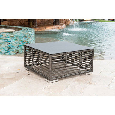 Outdoor patio table with a black top on a patio near a pool.