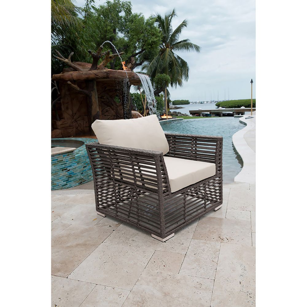Wicker chair with beige cushions by a pool with a water feature