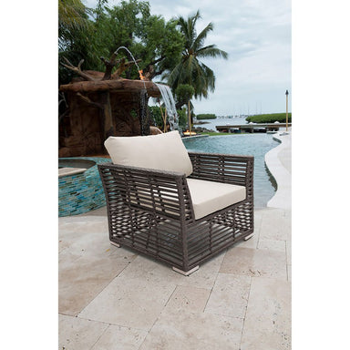 Wicker chair with beige cushions by a pool with a water feature