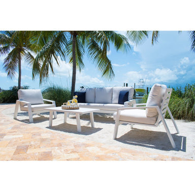 Outdoor patio set with chairs and table on a stone patio with palm trees and ocean view.
