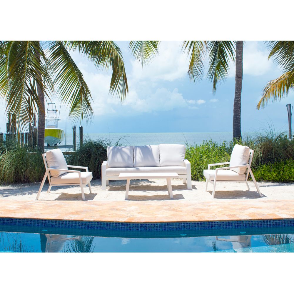 Outdoor patio set with white furniture by a pool, palm trees in the background