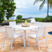 White outdoor dining set with chairs and table on a patio by a pool and ocean view.