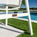 White chair with a brand logo on a grassy area near a pool
